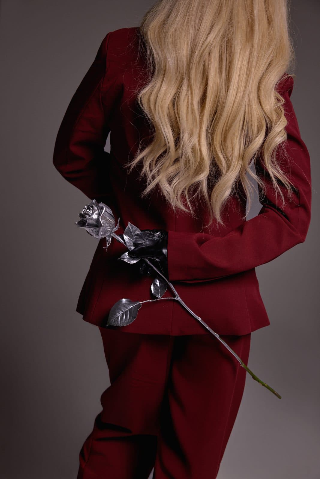A figure in a burgundy suit holding a silver rose